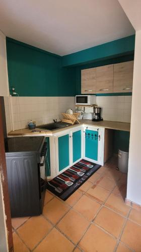 a kitchen with green walls and white cabinets at Villa dousè lavi in Sainte-Anne