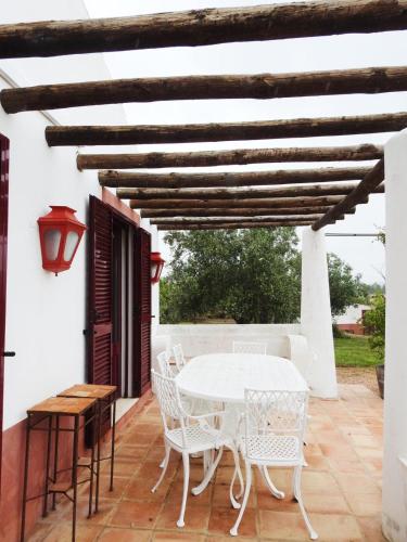 a white table and chairs on a patio with a wooden ceiling at Casas da Serra d'Ossa - Casa da Horta in Glória