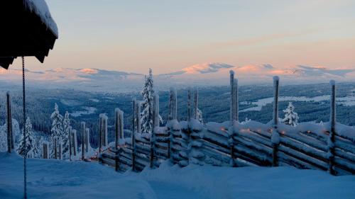 a fence covered in snow with mountains in the background at Liapark in Ål