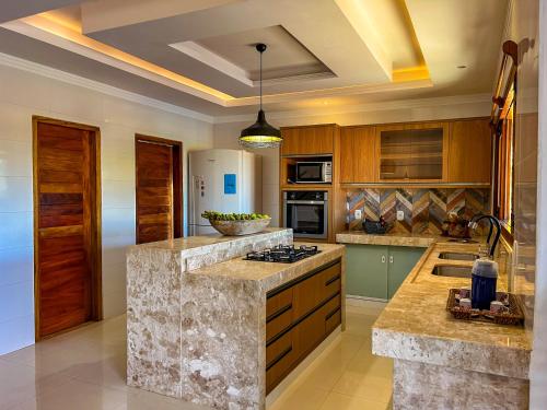 a large kitchen with wooden cabinets and granite counter tops at Pousada Refúgio Verde Trancoso in Trancoso