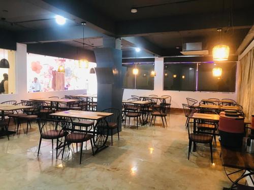 a dining room with tables and chairs and a large screen at Aquila Hotel and Convention by The Nexus in Patna