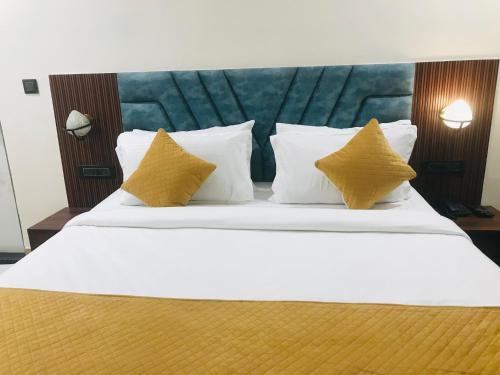 a bedroom with a white bed with yellow pillows at Aquila Hotel and Convention by The Nexus in Patna