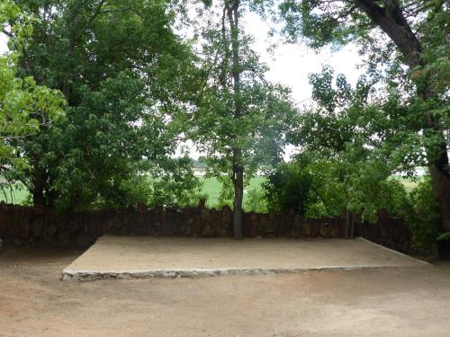 a park with trees and a stone fence at Nyime Safari Lodge Campsite in Divundu