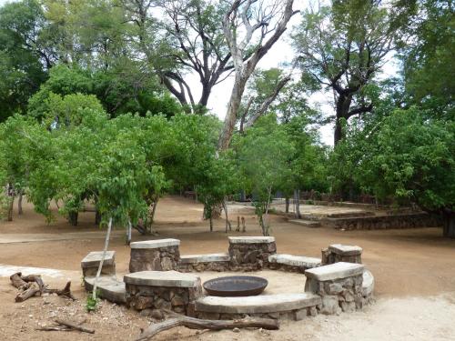 a stone fire pit in a park with trees at Nyime Safari Lodge Campsite in Divundu