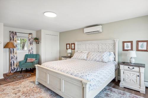 a bedroom with a white bed and a green chair at Lakeshore Vermont in Colchester