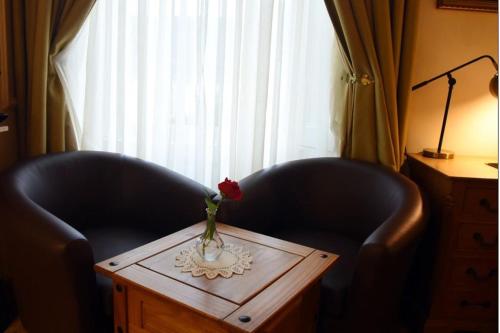 two black chairs and a table with a flower in a vase at The Old Bank Bruff Family Town House in Bruff
