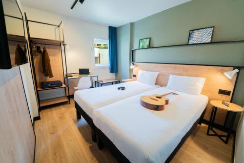 a hotel room with a bed with a guitar on it at Hotel ibis Guimaraes in Guimarães