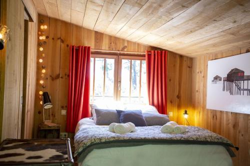 une chambre avec un lit avec des rideaux rouges et une fenêtre dans l'établissement La Cabane des pins, à Lège-Cap-Ferret