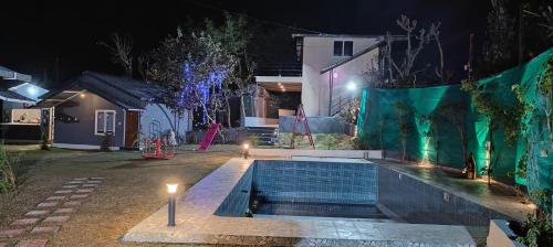 a swimming pool in the yard of a house at night at Oshins Retreat in Rājpur