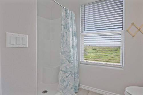 a bathroom with a shower curtain and a window at Spacious Beachfront 5BR with Gorgeous Ocean views - Blue Footed in Bolivar Peninsula
