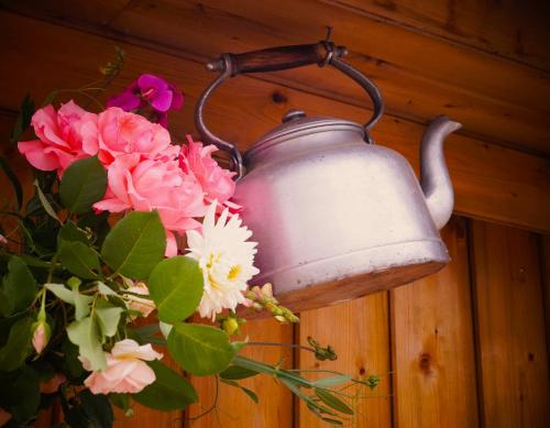 a kettle hanging on a wall with flowers at La volante Bouilloire in Saint-Rémy-la-Varenne