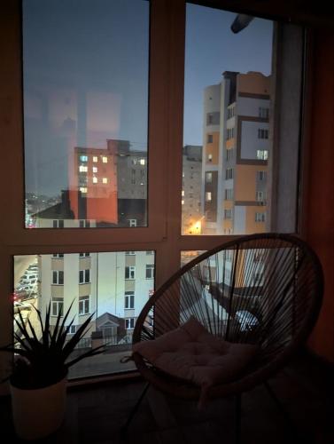 a chair in a window with a view of a city at 2-кім Новобудова, центр, провулок Лапушкіна , 9 in Khmelʼnytsʼkyy