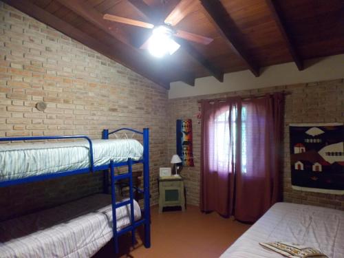 Un dormitorio con dos literas y una pared de ladrillo. en La cabañita de Maco, en Nono