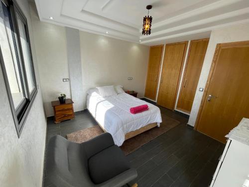 ein Schlafzimmer mit einem Bett und einem Stuhl in der Unterkunft Résidence villa in Agadir