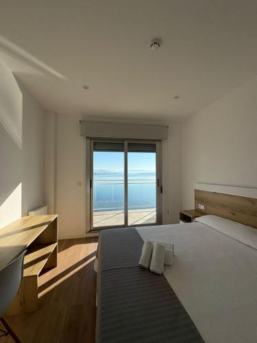 a bedroom with a bed with a view of the ocean at Apartamentos O Grove Awa Bay in O Grove
