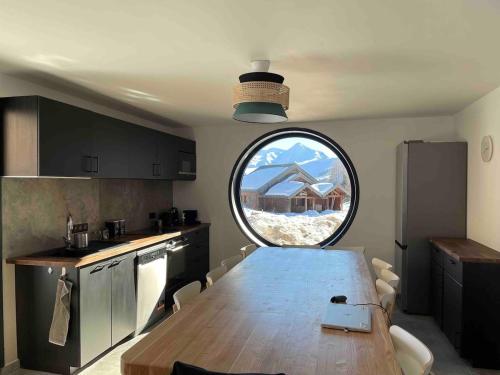 une cuisine avec une table et une fenêtre ronde dans l'établissement Chalet la petite ourse 110 m2 plein centre, à Villarembert