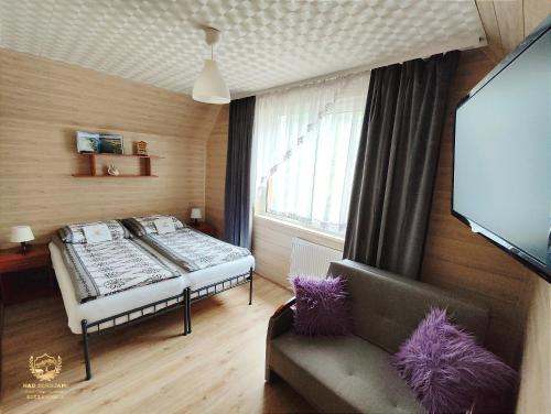 a bedroom with a bed and a couch and a tv at "Nad Zdrojami" Pokoje Kowalczyk in Szczawnica