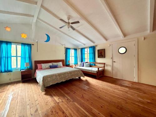 a bedroom with a bed and a table and windows at Casa Kubler in Puerto Ayora