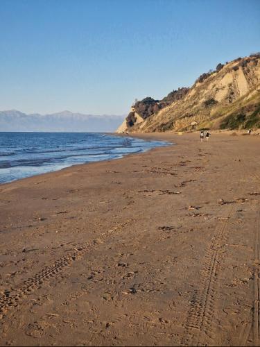 a beach with footprints in the sand and the ocean at Seasound in Agios Stefanos