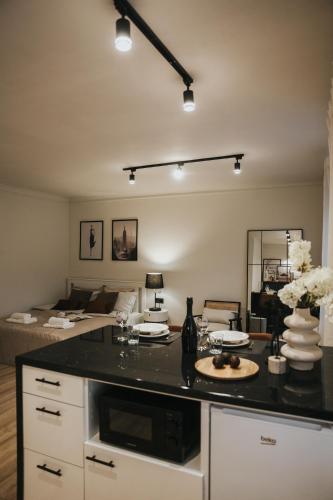 a kitchen with a black counter top and a living room at Lacplesa Street Apartment in Daugavpils