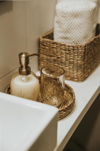 a bathroom counter with a bottle of soap and a basket at Lacplesa Street Apartment in Daugavpils