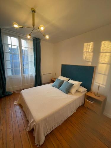 une chambre avec un grand lit blanc avec des oreillers bleus dans l'établissement La Pintade, au Tréport