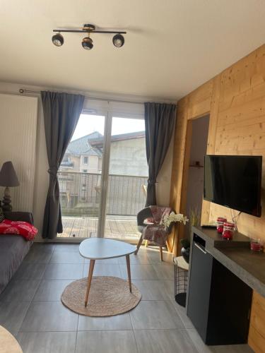 a living room with a couch and a tv and a table at Charmant appartement in Saint-Gervais-les-Bains