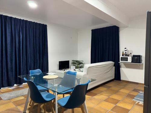 a living room with a glass table and blue chairs at Alforra Residence 2-Centro-Praias-Levadas in Câmara de Lobos