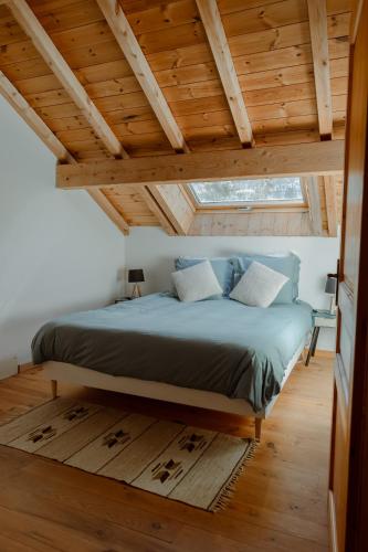 un lit dans une chambre avec un plafond en bois dans l'établissement Hébergement 4 étoiles Accès Pied des Pistes en Navette Gratuite, à Saint-Chaffrey