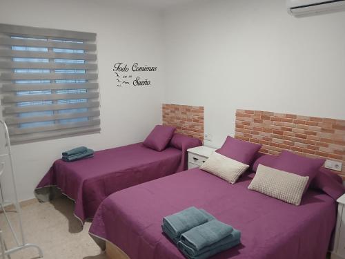 two beds in a room with purple sheets at Apartamentos de la mansión in Carmona