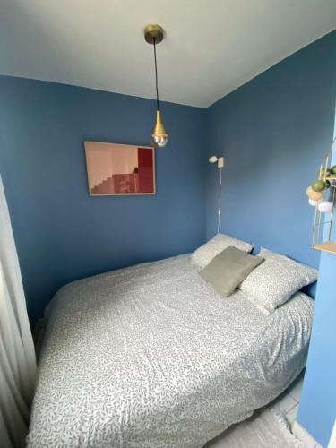 - une chambre bleue dotée d'un lit avec un mur bleu dans l'établissement Nid douillet, à Ouistreham