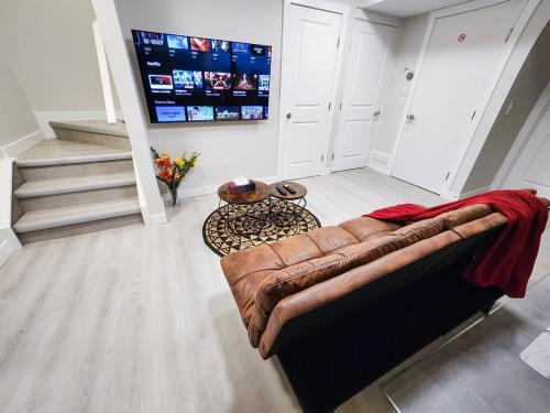 a living room with a leather couch and a television at Calgary Cozy Nest 2BR Suite in Calgary