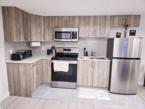 a kitchen with wooden cabinets and a stainless steel refrigerator at Calgary Cozy Nest 2BR Suite in Calgary