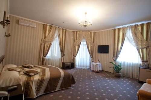a hotel room with a bed and two windows at Kleopatra VIP hotel in Kamianets-Podilskyi