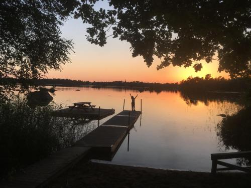 a person standing on a dock on a lake at sunset at Osaby Säteri in Tävelsås