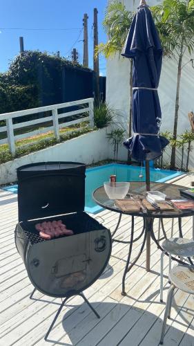a patio with a grill and a table and an umbrella at Suíte 1 - Zeh Guest house in Imbituba