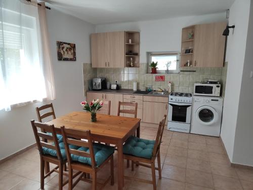 a kitchen with a wooden table and chairs and a stove at Tulipán Vendégház Harta in Harta