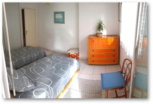 une chambre avec un lit, une commode et une chaise dans l'établissement L'Impérial, à Saint-Raphaël