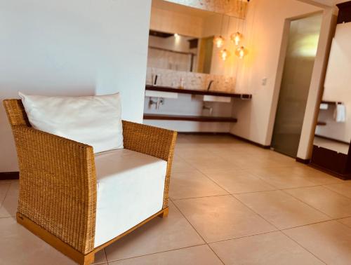 a wicker chair with a white pillow in a kitchen at Pousada Spa dos Amores in São Miguel do Gostoso