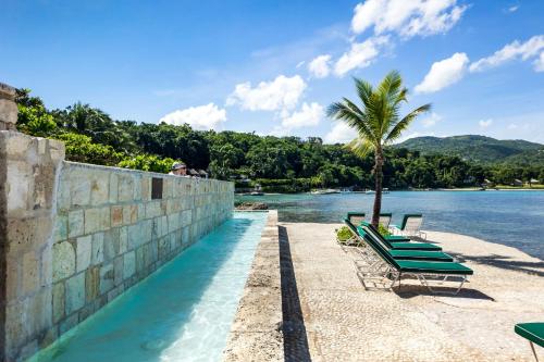 a row of chaise lounge chairs next to the water at Round Hill Hotel & Villas in Montego Bay