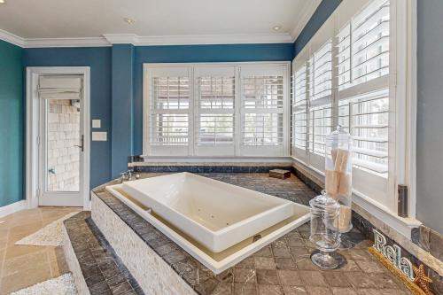 a large tub in a room with blue walls and windows at The Chancellery --- 6 Hall Ave in Dewey Beach