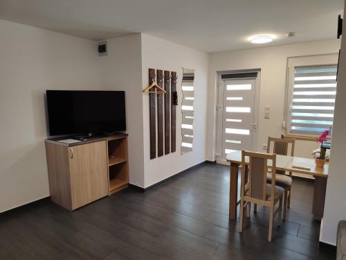 a living room with a flat screen tv and a table at Tulipán Vendégház Harta in Harta