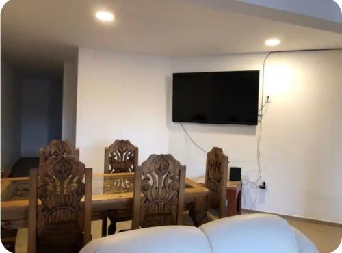 a living room with a table and chairs and a flat screen tv at Habitación privada Depa B in Jardines de la Hacienda
