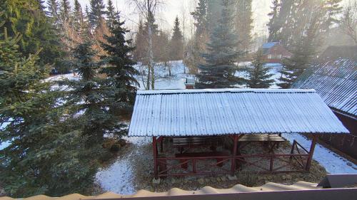 a snow covered yard with a building with a roof at Cabana Kristof Kulcsosház in Borzont