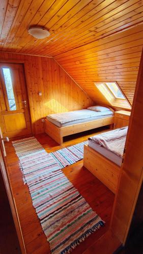 a small room with two beds and a rug at Cabana Kristof Kulcsosház in Borzont