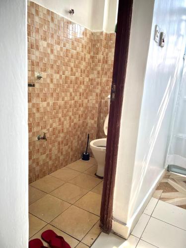 a bathroom with a toilet and a tiled floor at Cozy studio Milimani in Kisumu