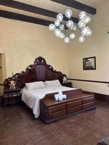 a bedroom with a large wooden bed with a chandelier at Hotel cuenca antigua in Mazamitla