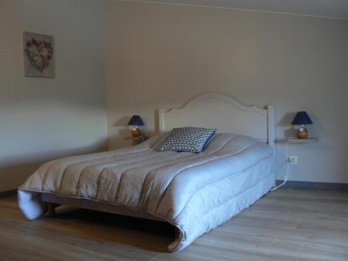 1 dormitorio con 1 cama blanca y 2 lámparas en la pared en La Calade, en Rosières