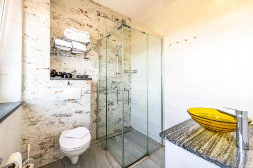 a bathroom with a toilet and a glass shower at Wels Inn Hotel in Wels