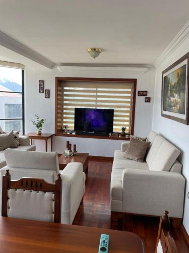 ein Wohnzimmer mit weißen Möbeln und einem Flachbild-TV in der Unterkunft Acogedor departamento cerca al Terminal in Loja